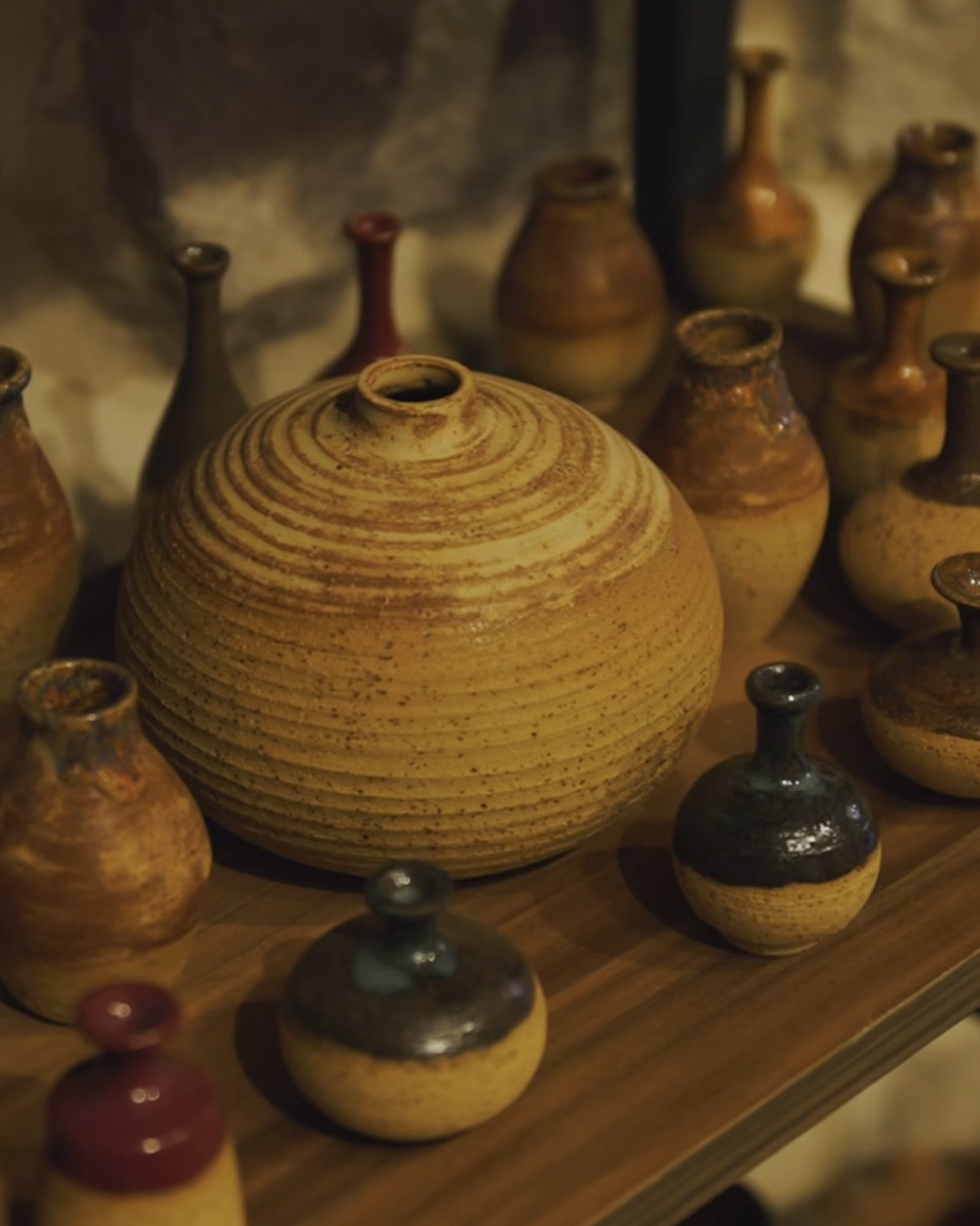 Handmade ceramic objects displayed on a wooden bench